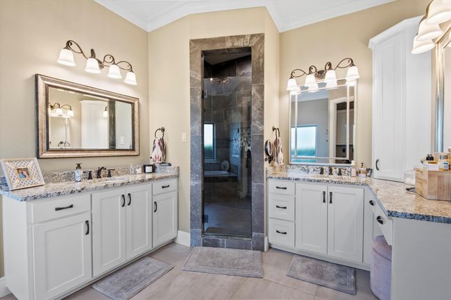 Primary Ensuite featuring a stall shower, crown molding, two vanities, and tile patterned floors | Image 19