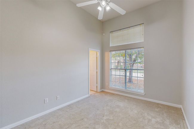 Unfurnished room featuring light carpet, baseboards, ceiling fan, and a towering ceiling | Image 26