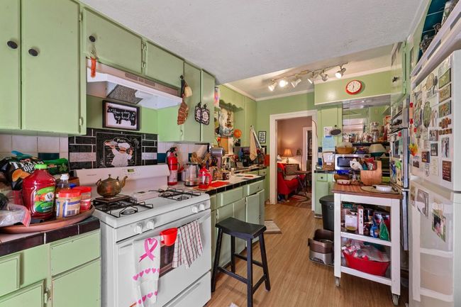 Kitchen with green cabinetry, tile counters, white gas stove, and light wood finished floors | Image 18