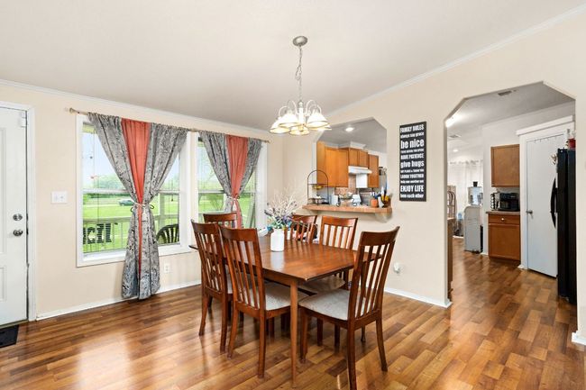 Dining space featuring arched walkways, crown molding, wood finished vinyl floors, and a chandelier | Image 7