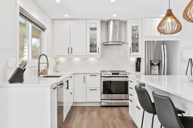 Kitchen with tasteful backsplash, wall chimney range hood, light wood-style floors, stainless steel appliances, and a sink | Image 13
