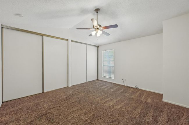 Unfurnished bedroom featuring carpet floors, a textured ceiling, vaulted ceiling, and multiple closets | Image 14