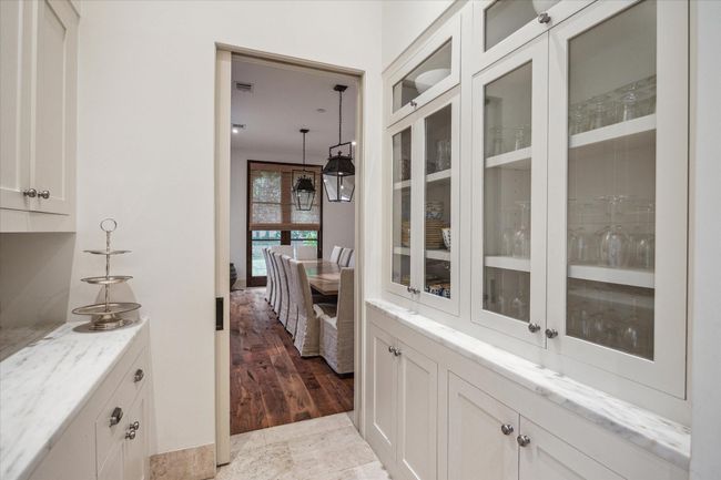 The butler's pantry between the kitchen and dining room with glass front cabinets and serving counter. | Image 19