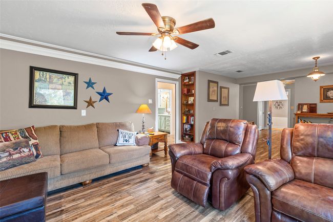 Living area with wood finished floors, a ceiling fan, and crown molding | Image 13