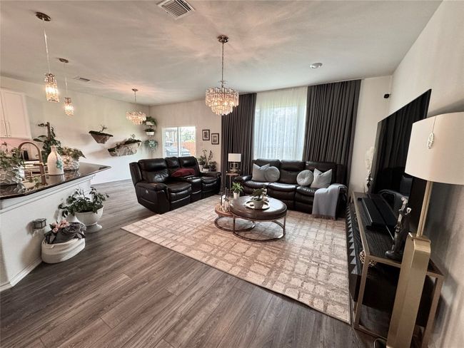 Living room with wood finished floors and a chandelier | Image 8