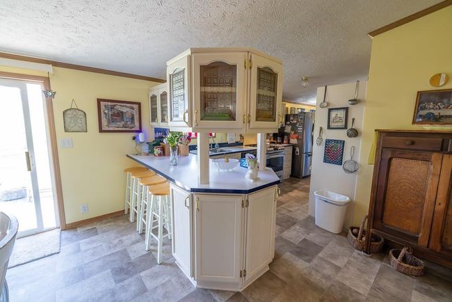Kitchen featuring glass insert cabinets, a breakfast bar, stainless steel appliances, a peninsula, and crown molding | Image 6