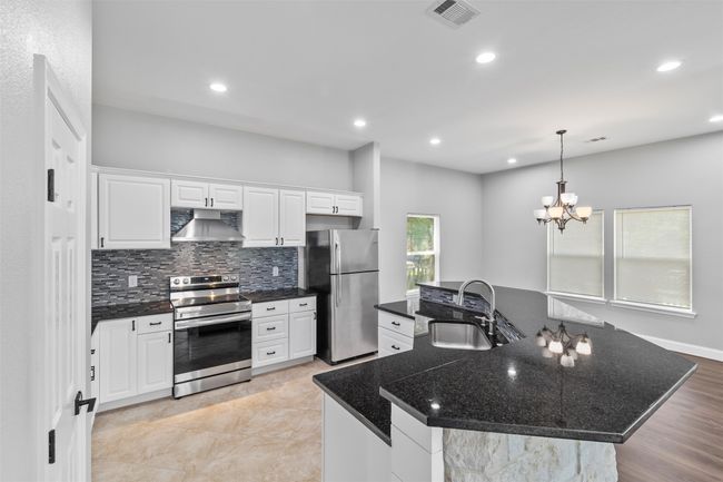 Kitchen with pendant lighting, backsplash, sink, white cabinetry, and appliances with stainless steel finishes | Image 10