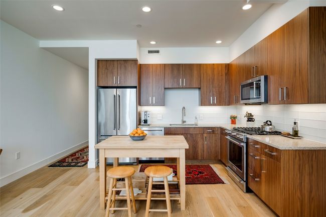 Kitchen with high quality appliances, decorative backsplash, light wood-style flooring, recessed lighting, and light stone counters | Image 4