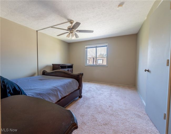 Bedroom featuring baseboards, carpet floors, a textured ceiling, and ceiling fan | Image 19