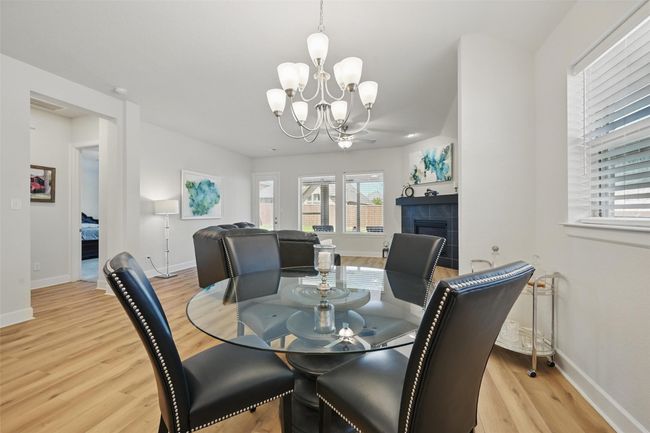 Dining area featuring wood finished floors, a chandelier, a fireplace, and baseboards | Image 11