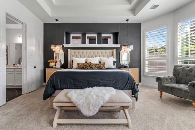 Carpeted bedroom featuring a chandelier, baseboards, ensuite bath, and a tray ceiling | Image 16