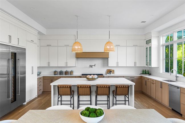 Kitchen featuring appliances with stainless steel finishes, a sink, a kitchen breakfast bar, a kitchen island, and light wood finished floors | Image 17