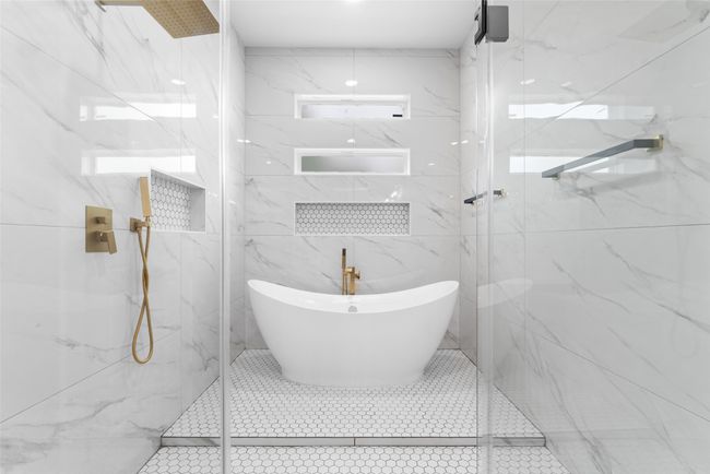 Full bath featuring a freestanding tub, a marble finish shower, and tile walls | Image 20