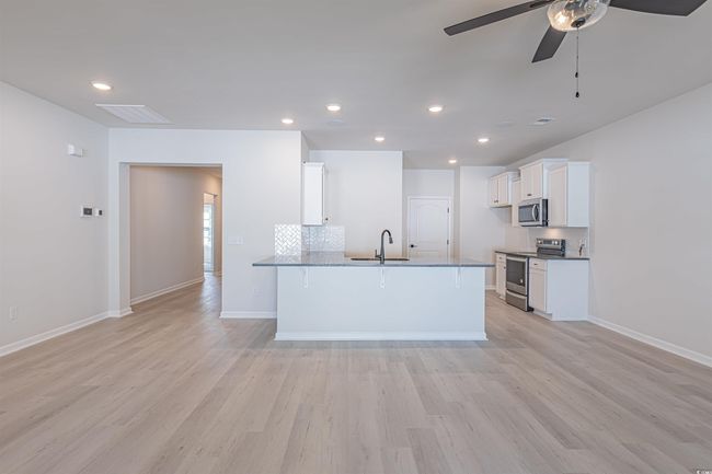 Kitchen with white cabinetry, stainless steel appliances, light wood-type flooring, and a sink | Image 21