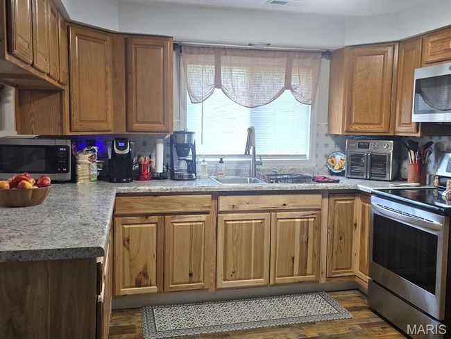 Kitchen with stainless steel appliances, dark wood-style flooring, and brown cabinets | Image 9