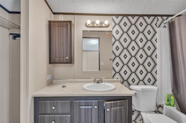 Bathroom featuring vanity, shower / tub combo with curtain, and a textured ceiling | Image 11
