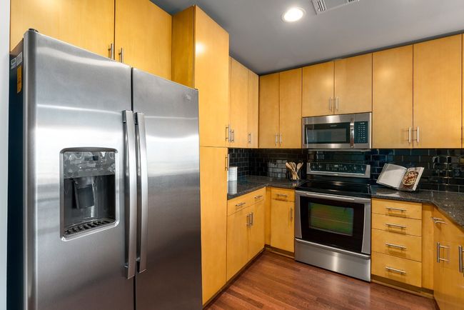 Kitchen featuring stainless steel appliances, dark wood finished floors, tasteful backsplash, dark stone counters, and recessed lighting | Image 8