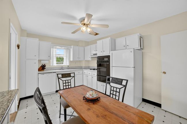 Kitchen with white appliances, light flooring, a ceiling fan, and white cabinets | Image 18
