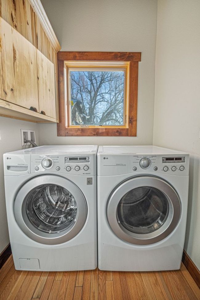 Laundry area featuring wood finished floors, washing machine and clothes dryer, cabinet space, and baseboards | Image 15