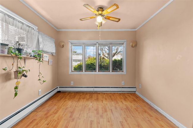 Empty room with crown molding, a baseboard heating unit, light wood-style floors, a baseboard radiator, and a ceiling fan | Image 16