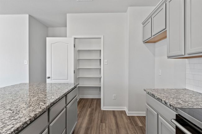 Kitchen featuring gray cabinets, dark wood-style floors, light stone counters, and decorative backsplash | Image 14