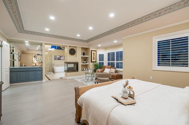 Bedroom with ornamental molding, light wood-style flooring, recessed lighting, and a multi sided fireplace | Image 19