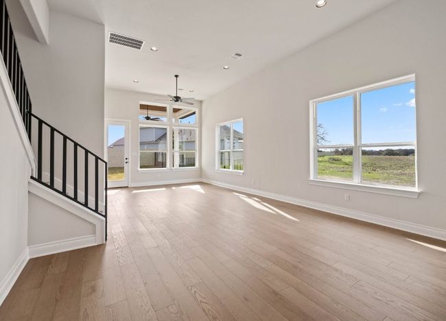 Unfurnished living room featuring visible vents, ceiling fan, baseboards, wood finished floors, and stairs | Image 7