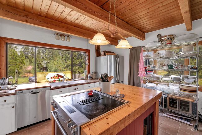 Kitchen with wood counters, light tile patterned flooring, stainless steel appliances, a wooden ceiling with exposed beams, and white cabinets | Image 19