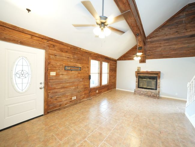 Entryway with a ceiling fan, wooden walls, a fireplace, and light tile patterned floors | Image 13
