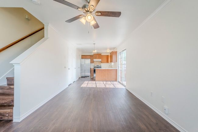 Unfurnished living room featuring wood finished floors, stairs, ornamental molding, and ceiling fan | Image 5