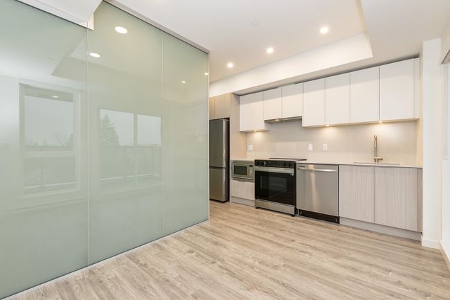 Kitchen with appliances with stainless steel finishes, a sink, light wood-style flooring, white cabinets, and modern cabinets | Image 6