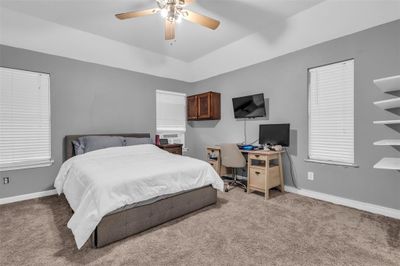 Bedroom with ceiling fan, light carpet, and a tray ceiling | Image 3