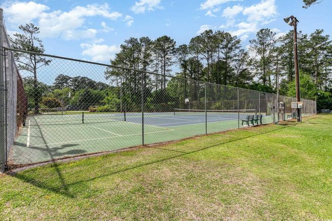 View of tennis court featuring fence and a lawn | Image 26