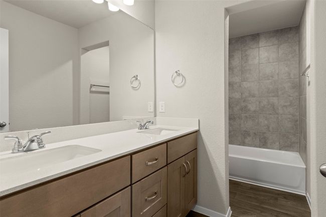 Full bathroom with wood finished floors, double vanity, and washtub / shower combination | Image 31