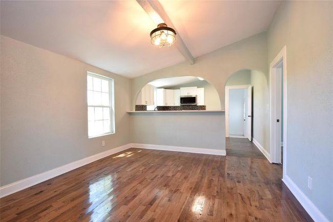 Unfurnished living room with beamed ceiling, dark wood-style flooring, and arched walkways | Image 4