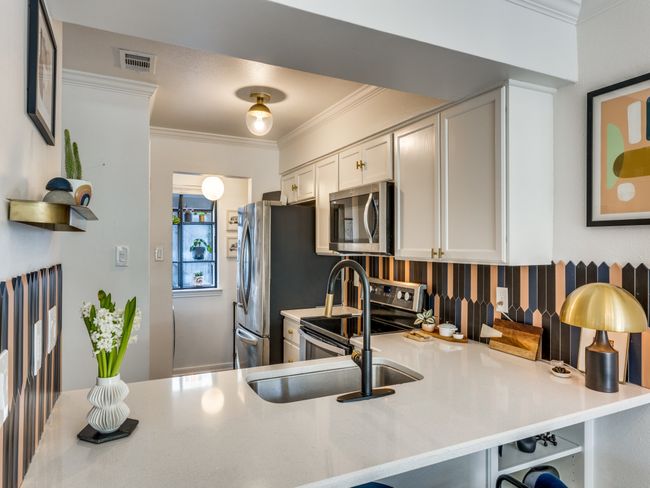 Kitchen with stainless steel appliances, white cabinets, ornamental molding, light countertops, and a peninsula | Image 4