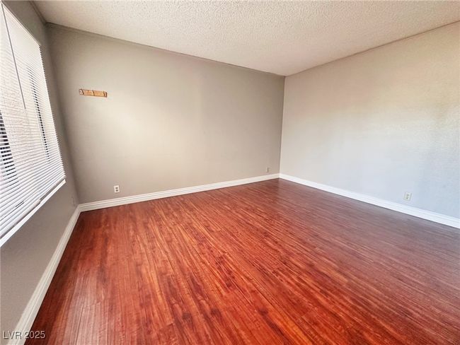 Empty room featuring dark wood-style floors, baseboards, and a textured ceiling | Image 11