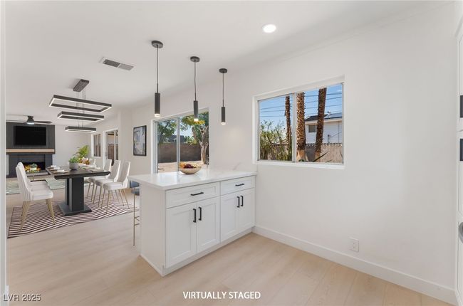 Kitchen featuring light wood-style flooring, white cabinetry, a peninsula, light countertops, and decorative light fixtures | Image 19