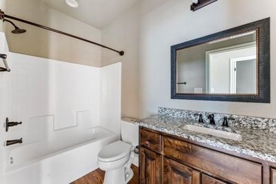 Full bathroom featuring shower / tub combination, vanity, wood-type flooring, and toilet | Image 3