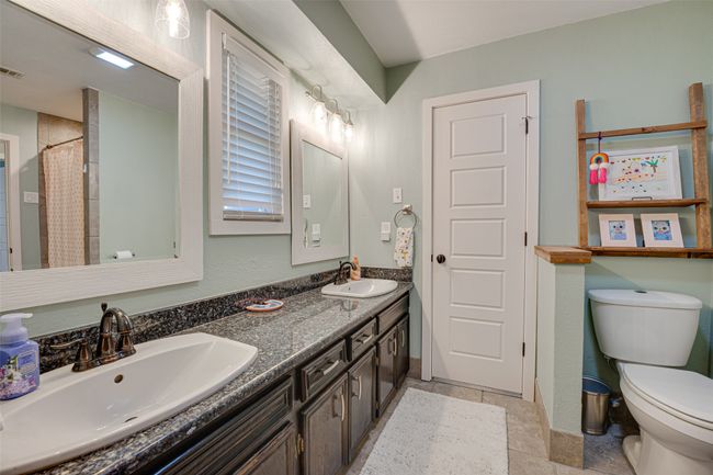 Full bathroom featuring double vanity, curtained shower, and stone tile flooring | Image 24
