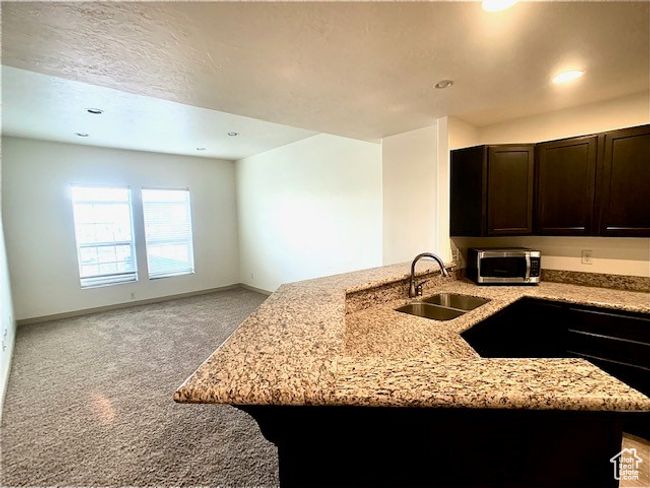 Kitchen with stainless steel microwave, light stone countertops, light colored carpet, dark brown cabinets, and recessed lighting | Image 4