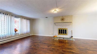 NICELY SIZED LIVING ROOM WITH LARGE WINDOW FOR NATURAL LIGHTING FEATURING A BRICK FIREPLACE | Image 3