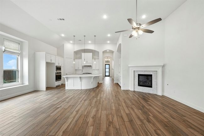 Kitchen featuring open floor plan, tile flooring, backsplash, a fireplace, and light countertops | Image 13