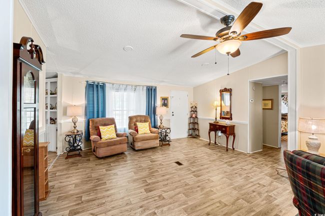 Sitting room with a ceiling fan, light wood-type flooring, and a textured ceiling | Image 15