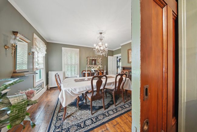 Dining space featuring radiator, a chandelier, hardwood / wood-style flooring, and ornamental molding | Image 18
