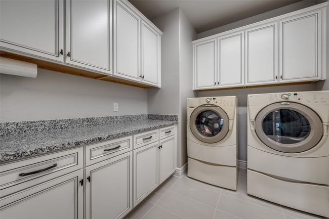 Laundry Room with light tile patterned floors, cabinets and granite countertop | Image 17