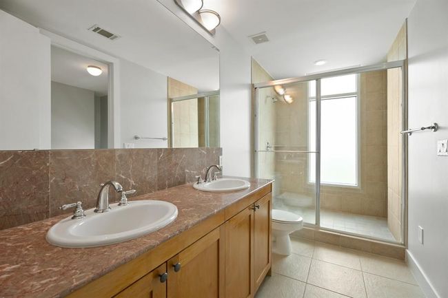The primary bedroom has convenient twin sinks and a spacious shower. | Image 10