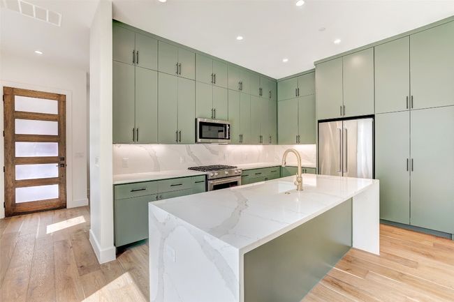 Kitchen featuring green cabinetry, high end appliances, recessed lighting, tasteful backsplash, and light wood-style floors | Image 14