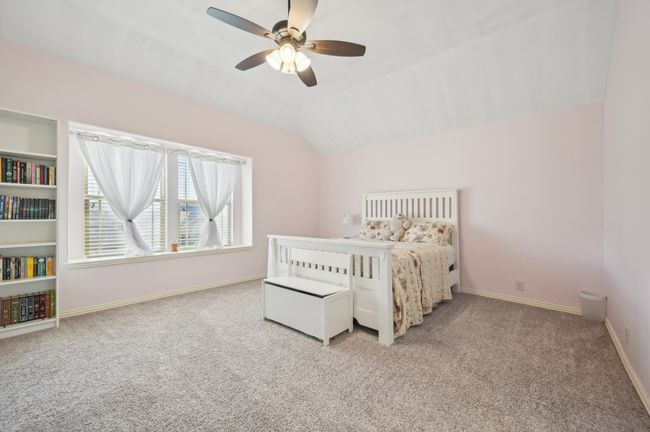 Bedroom with baseboards, ceiling fan, light colored carpet, and vaulted ceiling | Image 31
