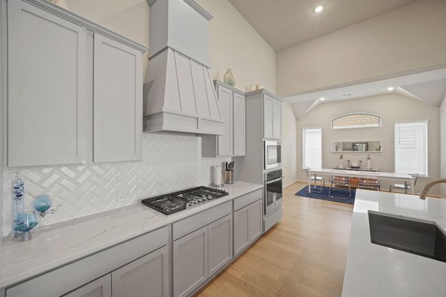 The kitchen features light cabinets, white tile backsplash, and stainless steel appliances creating a clean and timeless aesthetic. | Image 9